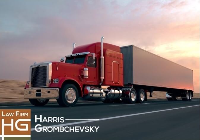 A truck with a red cap and white trailer driving at sunset